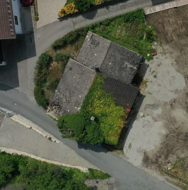 Dachansicht eines Hauses mit grüner Vegetation und angrenzendem Kiesweg.