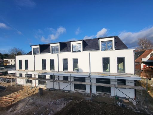 Neubau mit mehreren Fenstern und einem Flachdach, umgeben von Baugerüsten.