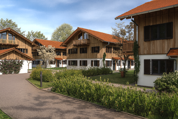 Blick auf eine Almhüttensiedlung mit Holzfassaden und begrünten Gartenbereichen.