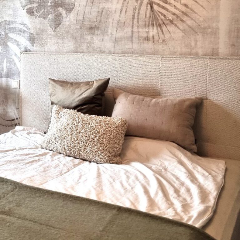 Wohnen Ein Bett mit mehreren Kissen und einer gestreiften Decke in einem hellen Raum.