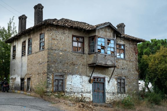 Verfallenes, zweigeschossiges Haus mit Klinkerfassade und Fensterläden.